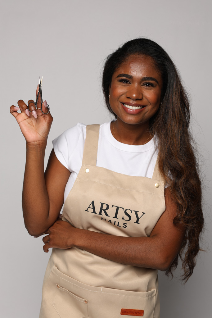 Natalia Granja holding manicure scissors in her Artsy Nails apron